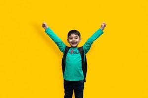 Lindo niño feliz de 7 años con mochila escolar sosteniendo libros en fondo liso para el concepto de educación foto