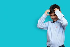 Sad and aggressive Little sick boy holding his head with his hand on plane isolated background with copy space photo