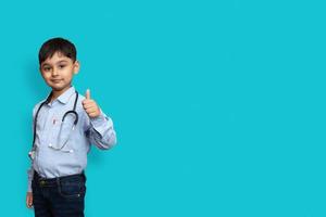 Smiling child boy doctor with glasses plain background. Male doc in white shirt doing thumbs-up. Healthcare health medicine concept. Mock up copy spac photo