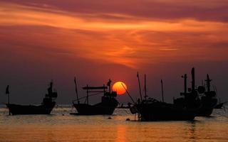 Barco de madera de la pesca de la silueta con la iluminación baja del cielo del atardecer. foto