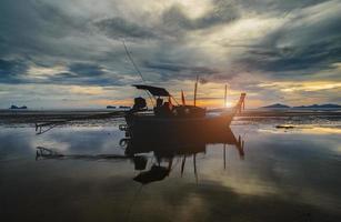 Barco de madera de pesca con luz tenue del cielo al atardecer. foto