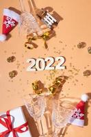 Festive new year flat lay with numbers 2022 and hard shadows with glasses and shiny decor photo