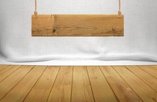 Wood table with hanging wooden sign on white fabric background photo