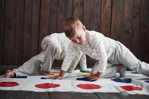 Two of happy children playing at twister in house. Brother and sister have a fun time in holiday photo