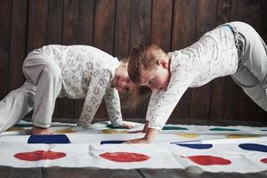 Two of happy children playing at twister in house. Brother and sister have a fun time in holiday photo
