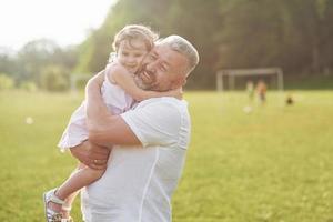 A cute little girl is spending time with her beloved grandfather in the park photo