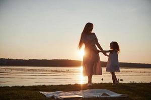 Mom plays with her baby on holidays near the ocean, silhouettes at sunset photo