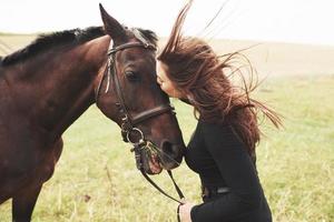 una niña feliz se comunica con su caballo favorito. la niña ama a los animales y a montar a caballo foto