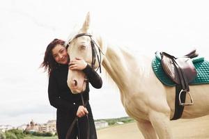A happy girl communicates with her favorite horse. The girl loves animals andhorseback riding