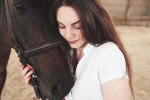 A happy girl communicates with her favorite horse. The girl loves animals andhorseback riding photo