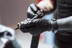 Artist holding tattoo machine in his studio, he is ready to accept the client photo