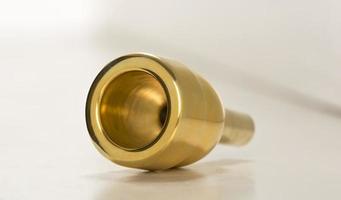 Mouthpiece for trombone, golden color on a white background.