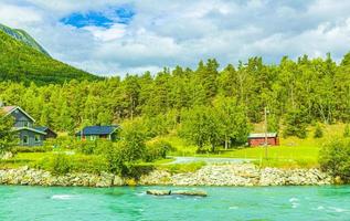 El agua de deshielo turquesa fluye en un río a través de una aldea en Noruega.