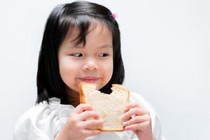 Happy beautiful girl eating slice bread. Child enjoy eating with breakfast. photo