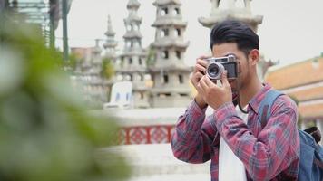 Asian man tourists walking traveling and using film camera taking a photo in temple Thailand. video