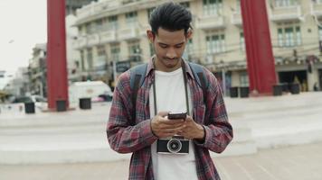 turistas solo de homem asiático em pé usando smartphones, verificando as mídias sociais. video
