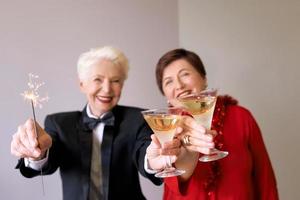 dos hermosas mujeres mayores maduras con estilo celebrando el año nuevo. diversión, fiesta, estilo, concepto de celebración foto