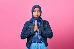retrato, de, tristeza, joven, mujer asiática, actuación, rezando, gesto, en, fondo rosa foto