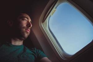 Pensive man looking outside through the window of an airplane photo