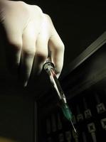 Hand holding dentist syringe to give anesthetic injection, low key photo