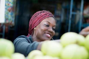 smiling young woman choosing apple  at street market.