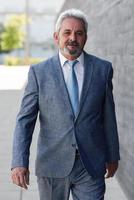 Senior businessman walking outside of modern office building. photo