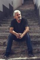 Mature man sitting on steps in urban background photo