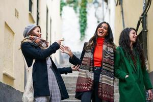 Multiethnic group of three happy woman walking together outdoors photo