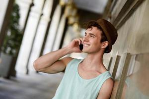 atractivo joven con sombrero hablando por el teléfono móvil foto