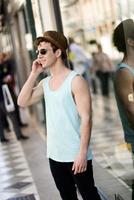 Attractive young man wearing hat talking on the mobile phone photo