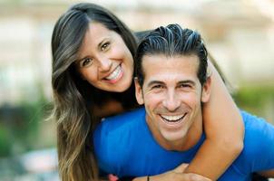 Smiling young man piggybacking his pretty girlfriend photo