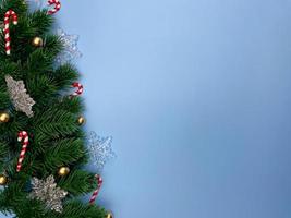 Christmas decorations, pine tree leaves, golden balls, snowflakes, golden berries on blue background photo