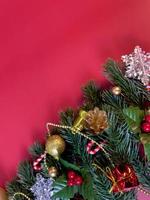 Christmas decorations, pine tree leaves, golden balls, snowflakes, golden berries and red berries on red background photo
