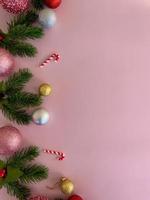 Christmas decorations, pine tree leaves, golden balls, snowflakes, red balls on pink background photo