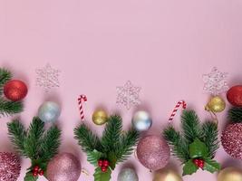 adornos navideños, hojas de pino, bolas doradas, copos de nieve, bolas rojas sobre fondo rosa foto