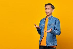 Portrait of asian man surprised with confused and displeased expression on yellow background photo