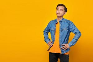 Portrait of confused asian man looking sideways on yellow background photo