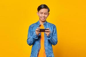 Portrait of happy young asian man playing video game on mobile phone photo