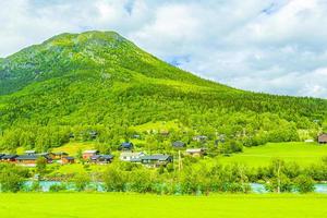 Turquoise meltwater flows in a river through village in Norway. photo