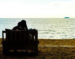 Amor de pareja de silueta con vista al mar - filtro de efecto vintage foto