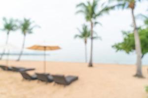 Silla de playa de desenfoque abstracto en la playa con mar océano de fondo - concepto de viajes y vacaciones foto