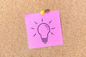 Bright Idea or Creative process concept. Light bulb drawing on sticky note on cork board photo
