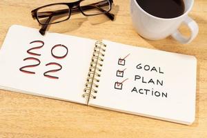 New year 2022 goal, plan, action text on notepad on wooden desk. Motivational checklist concept photo