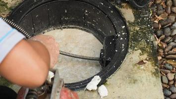 Drain cleaning. Plumber repairing clogged grease trap with auger photo