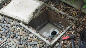 Drain cleaning. Plumber repairing clogged grease trap with auger photo