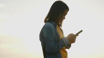 Asian woman scrolls through social media feed on a smartphone. video