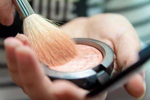 Close up of woman hands holding makeup brush and blush box photo