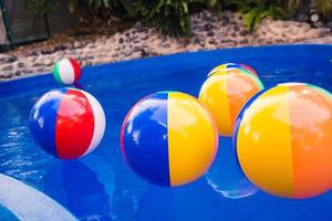 coloridas pelotas de playa flotando en la piscina foto
