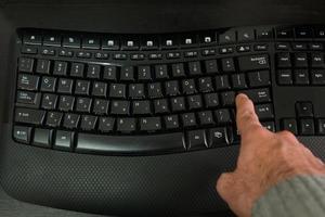 Hombre escribiendo en un teclado con letras en hebreo e inglés foto