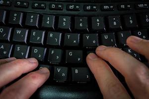 Man typing on a keyboard with letters in Hebrew and English photo